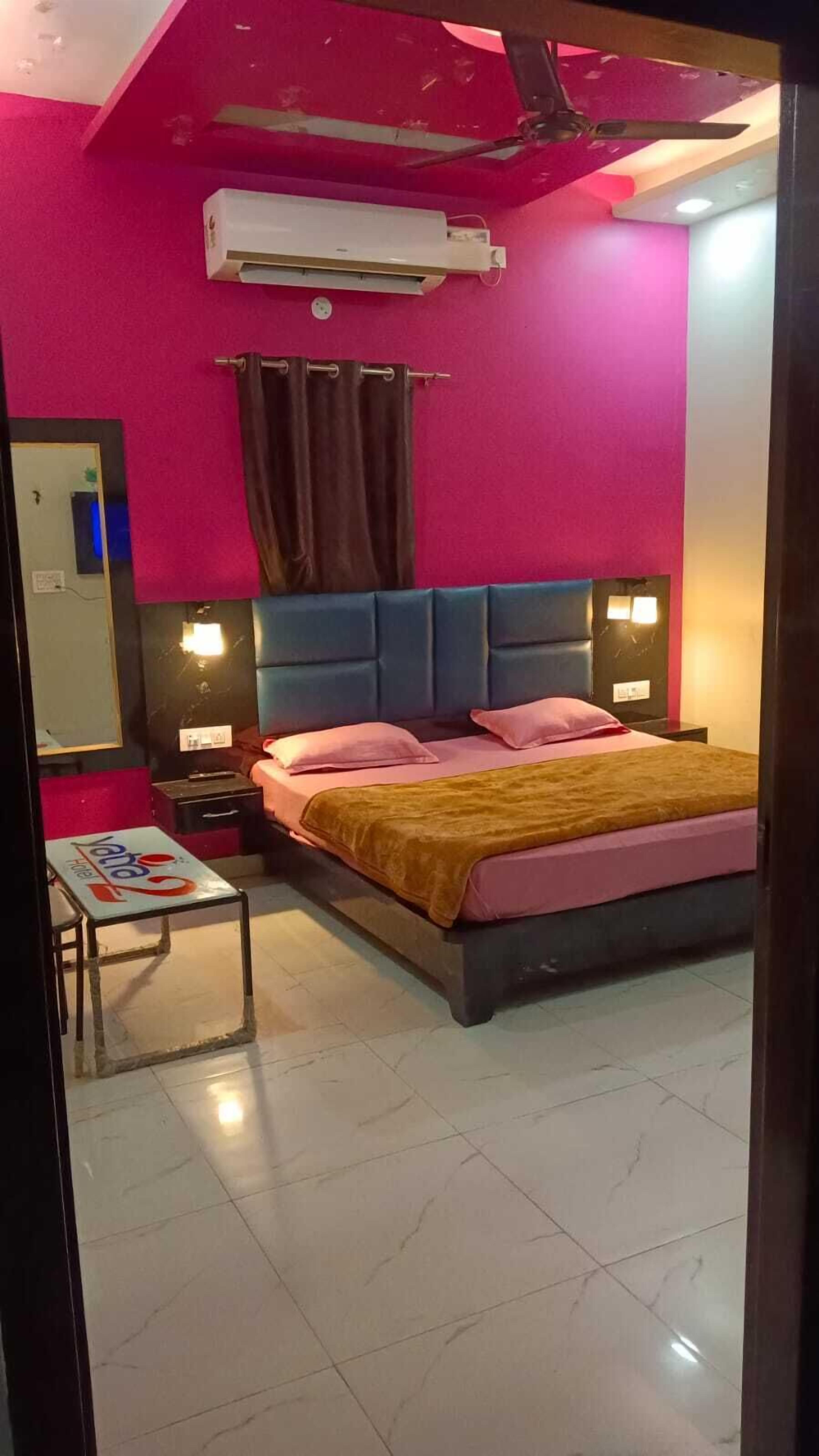 Un dormitorio con una cama, una mesita de noche, una pequeña mesa y un espejo.