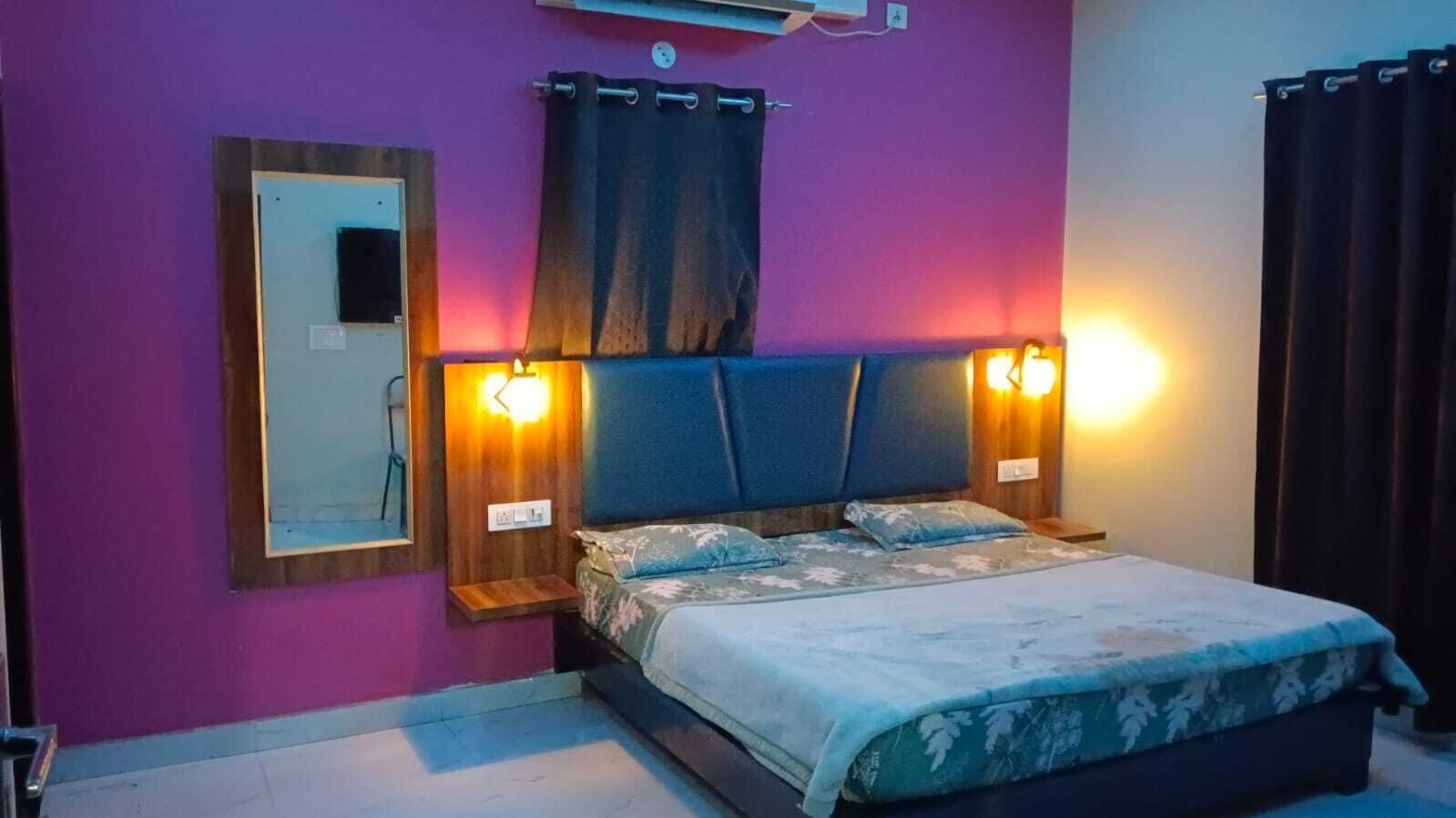 A bedroom with a bed, two bedside tables, a mirror, and a wall-mounted air conditioner.