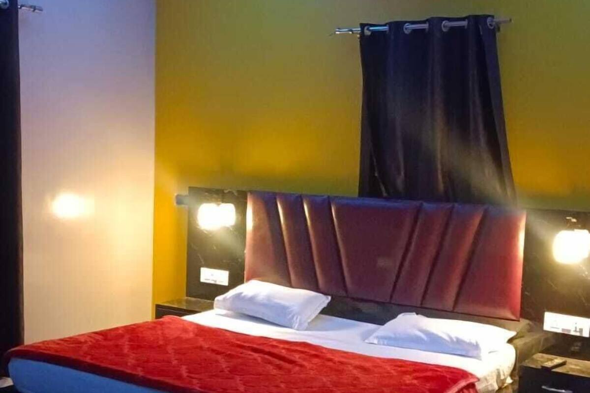 A hotel room with a bed, ceiling fan, air conditioning unit, and bedside lamps.