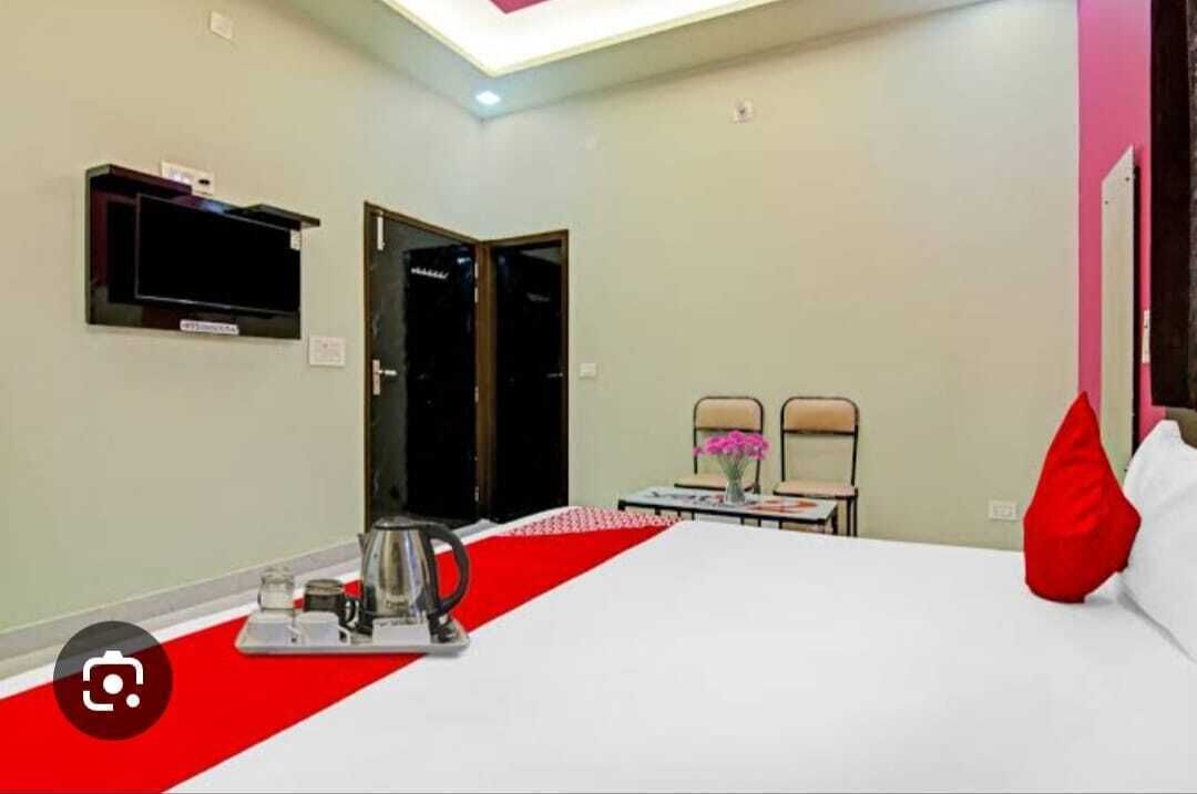 A hotel room with a bed, a TV mounted on the wall, a coffee maker, and a red and white striped area rug.