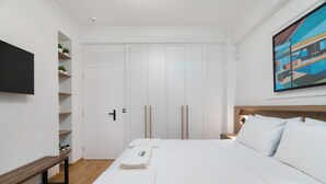 A modern hotel room with a large bed, a bench, a TV, and a painting on the wall. - Alexandra's Unique Apartment (Athens)