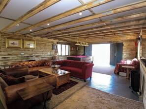Amplia sala de estar con techo de madera, mesa de billar, sofás de cuero y mesa de billar.