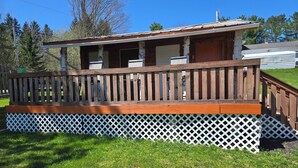 A wooden deck with a white lattice base, a porch, and a small attached structure.