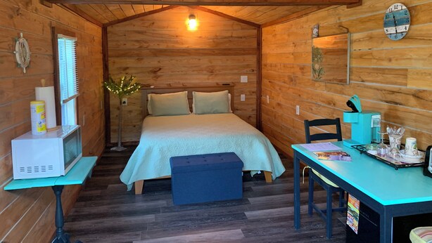 Una habitación acogedora estilo cabaña, con una cama, una mesita y un escritorio con silla.