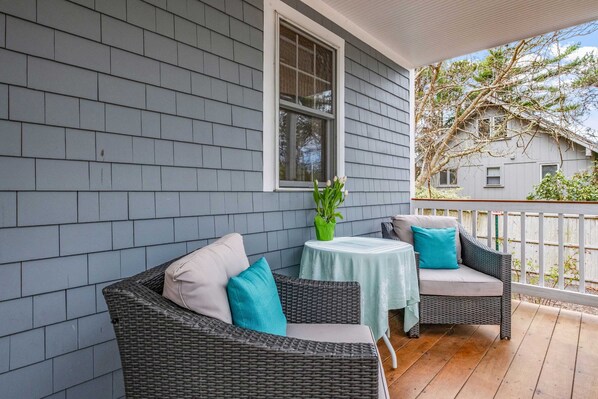 A porch with wicker furniture, a small table, and a window.