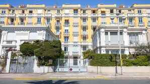 A row of yellow and white buildings with balconies, a gated entrance, and a clear blue sky. - HappyFew Palazzo Suite (Nice)