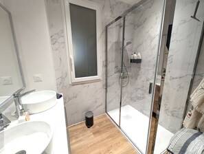 A modern bathroom with a glass shower enclosure, a sink, and a mirror.