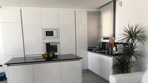 Eine moderne Küche mit weißen Schränken, einer schwarzen Arbeitsplatte und einem eingebauten Backofen.
