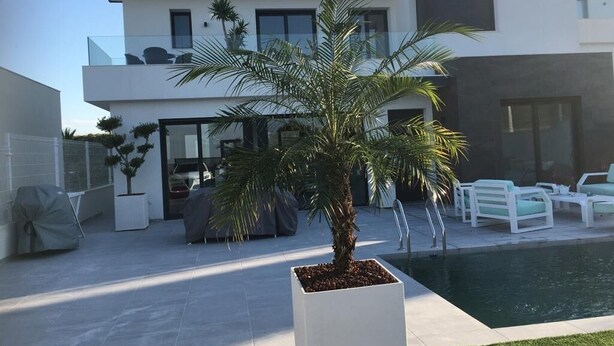 Ein modernes Haus mit Pool, Gartenmöbeln und einem gepflegten Garten.