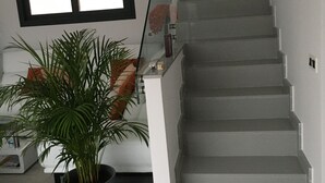 Eine Treppe mit modernem Design, ein Blumentopf und ein Fenster mit Rollläden.