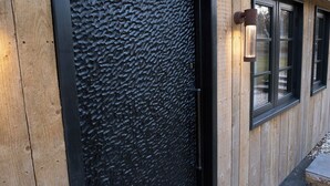 A wooden exterior with a textured black door and windows.