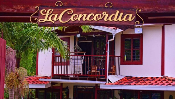 A building with a sign reading "La Concordia" and a balcony with chairs.