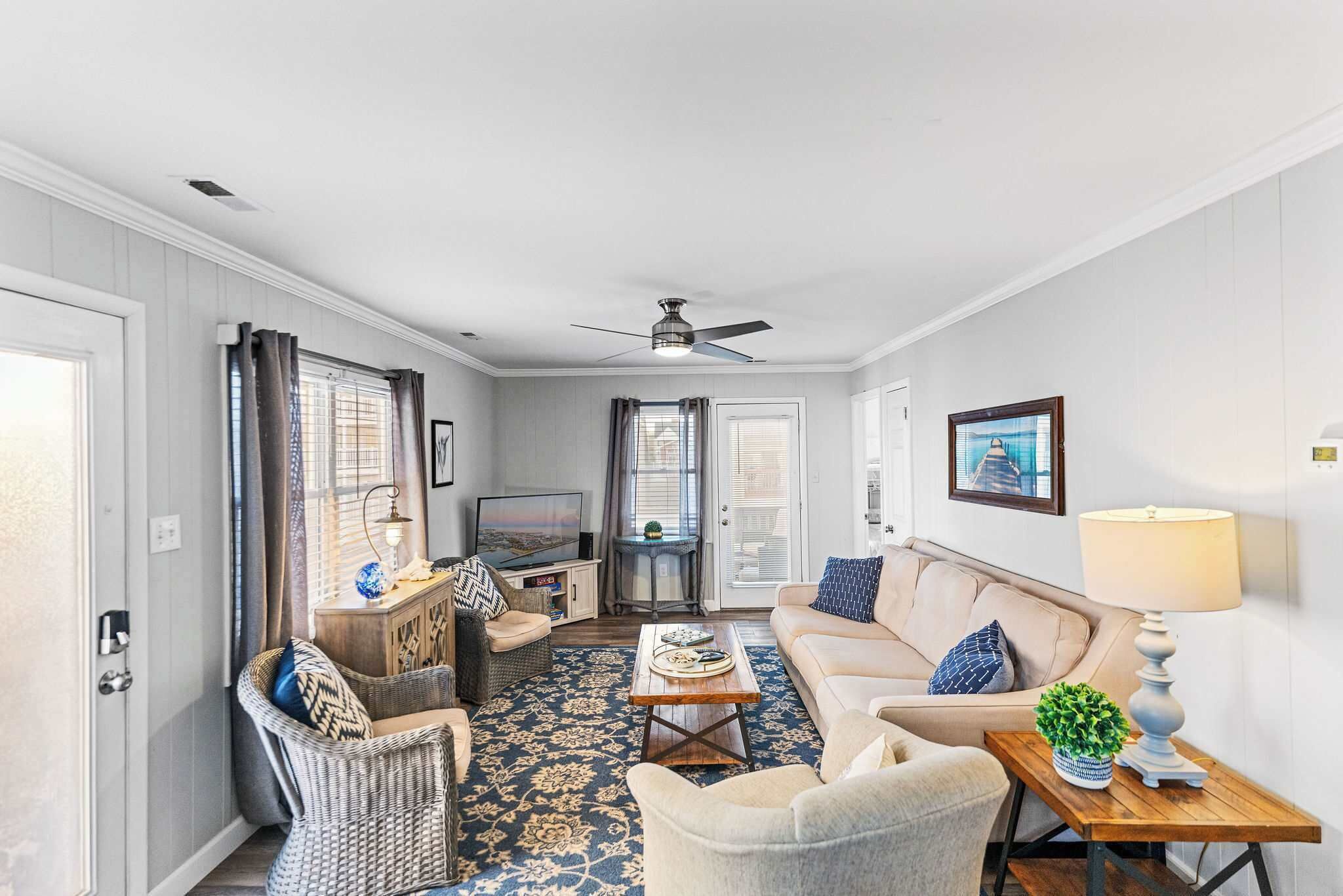 A living room with a sofa, armchair, coffee table, television, and decorative items.