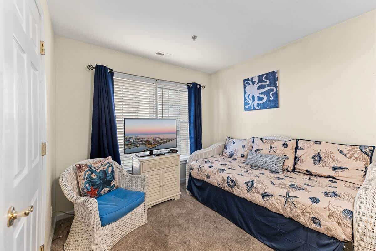 Un dormitorio con cama, televisión, sillón y cómoda.
