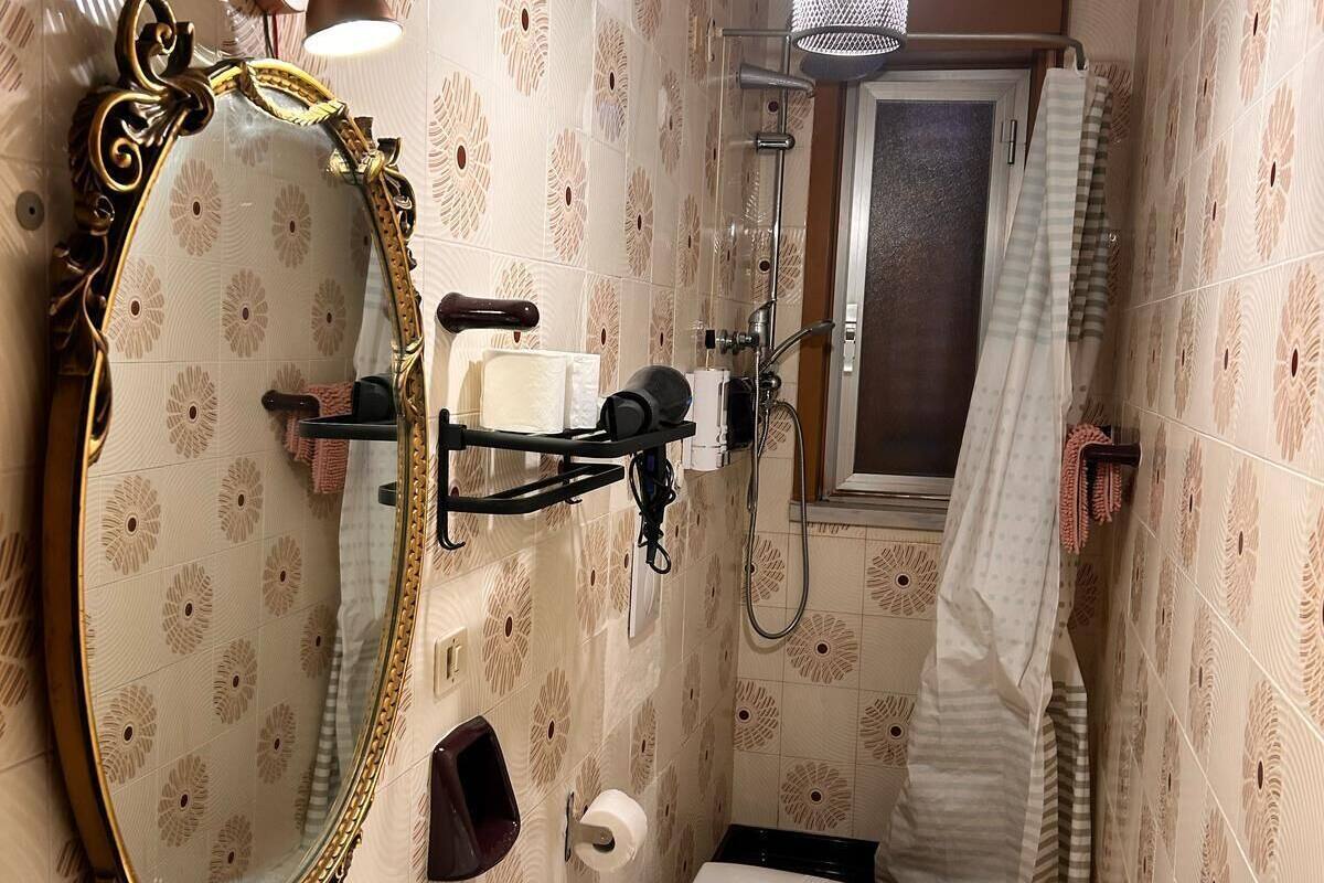 A bathroom with a white sink, a toilet, a mirror with an ornate frame, a shower with a glass door, and a towel hanging on the wall.