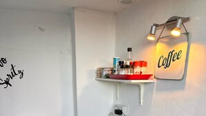 A compact kitchen with a coffee sign, a white cabinet with dishes, a black toaster, and a wooden countertop. - Casa Di Sylwia (Termini Imerese)