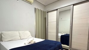 A bedroom with a bed, a blue blanket, a white pillow, a white wall, a ceiling fan, and a sliding door. - Casa Davisis 2  Jalapao e aeroporto (Palmas)