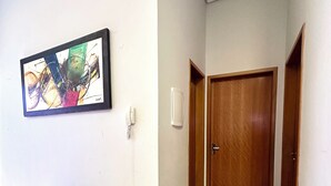 A hallway with a blue bench, a wall-mounted phone, and a wooden door. - Casa Davisis 2  Jalapao e aeroporto (Palmas)