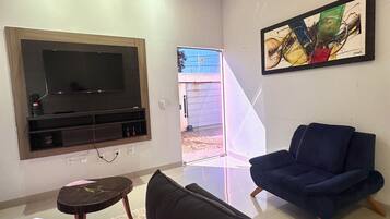 Un salon moderne avec un téléviseur à écran plat, un canapé bleu et un tableau accroché au mur.
