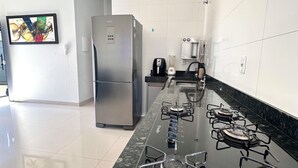 A modern kitchen with a stainless steel refrigerator, a gas stove, and a coffee maker. - Casa Davisis 2  Jalapao e aeroporto (Palmas)
