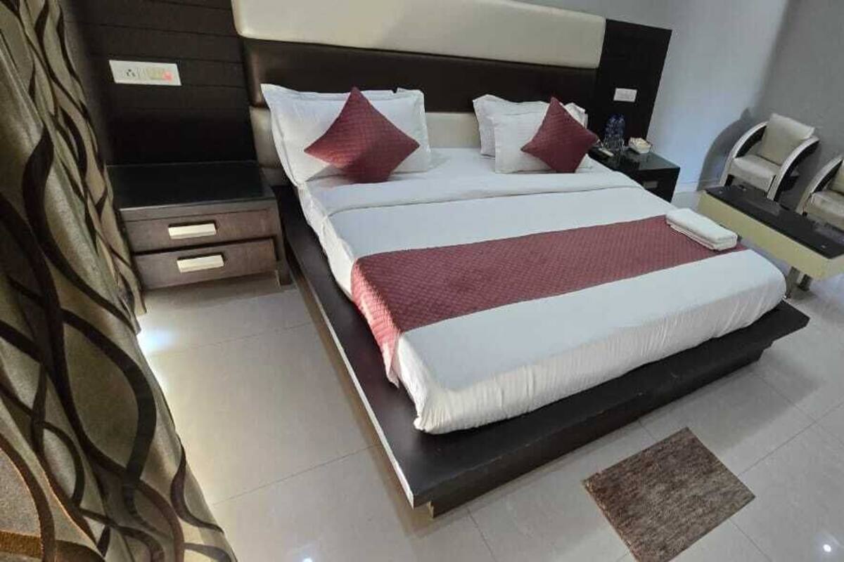 A modern hotel room with a large bed, two bedside tables, a desk, and a chair.