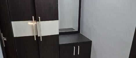 A bedroom with a wardrobe, a mirror, and a bed.