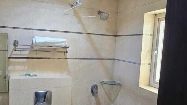 Ein Badezimmer mit Toilette, Dusche, Handtuchhalter und einem Fenster.