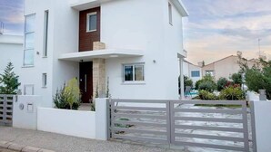 A modern two-story house with a white exterior, a wooden accent wall, and a gated driveway. - Aqua Luxe Ayia Napa Protaras Villa With Sea View (Paralimni)