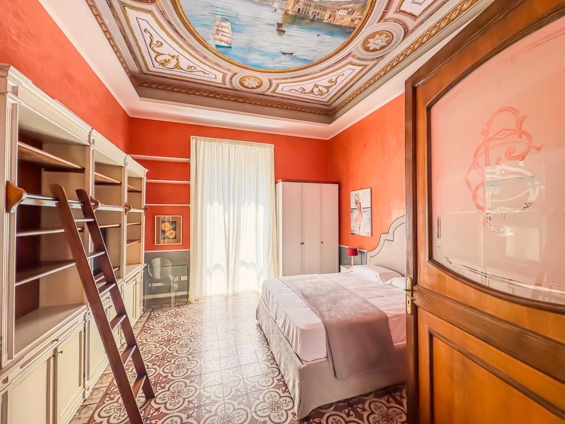 A room with a bed, a wardrobe, a ladder, and a ceiling with a mural.