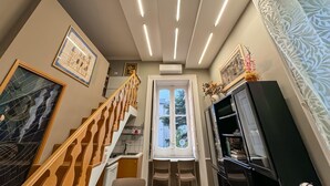 A modern interior with a staircase, a dining area, and a television. - YourHome - Chiara's Apartment Sorrento 3 (Piano di Sorrento)
