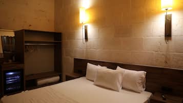 A hotel room with a large bed, a wardrobe, and two wall-mounted lights.