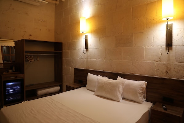 A hotel room with a large bed, a wardrobe, and two wall-mounted lights. - Tîsa Konağı (Halfeti)