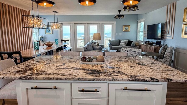 A spacious living area with a large marble island, a dining table, and a seating arrangement. - 7 Seas Ocean Breeze Sleeps Kitchens St George Island Pet Friendly Family (Eastpoint)