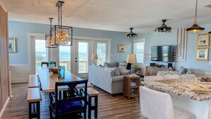 A spacious living area with a dining table, sofa, and kitchen island. - 7 Seas Ocean Breeze Sleeps Kitchens St George Island Pet Friendly Family (Eastpoint)
