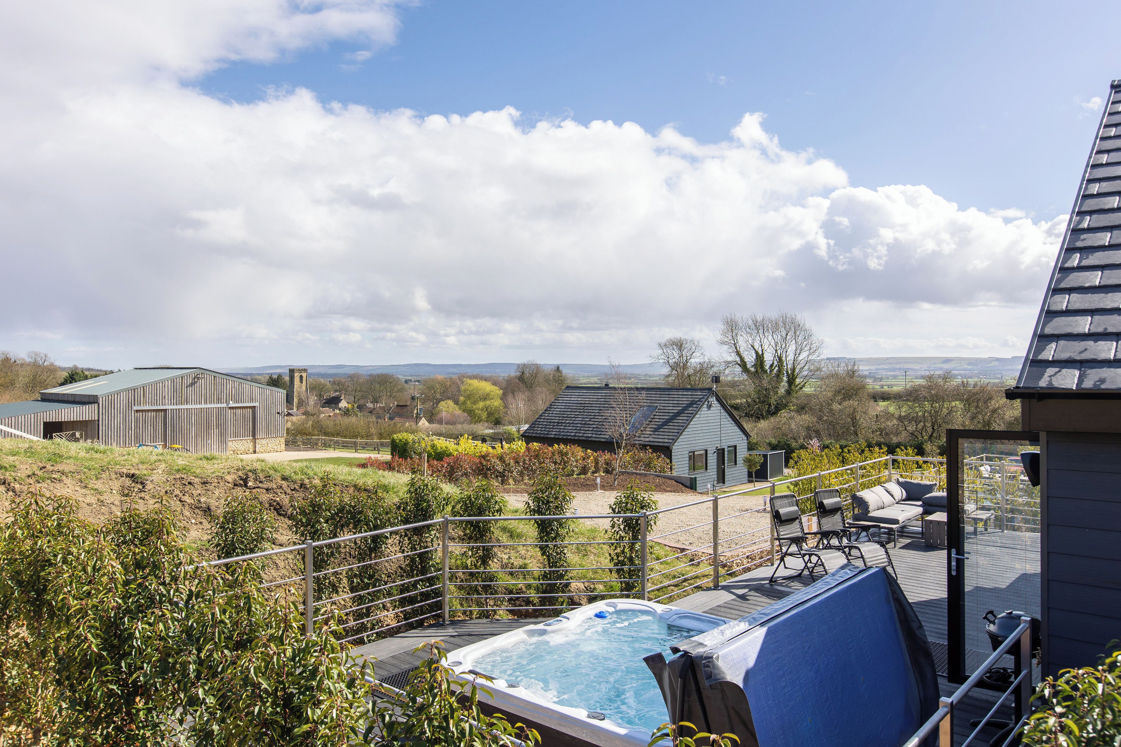 Une terrasse sur le toit dotée d’un jacuzzi, de coins salon extérieurs et offrant une vue sur le paysage environnant.