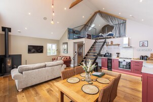 A spacious living area with a sofa, dining table, and a staircase leading to an upper level.