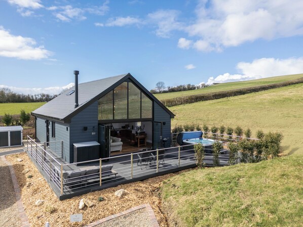 Una casa moderna con un amplio ventanal de cristal, una terraza y un jacuzzi.