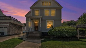A two-story house with a front porch, a garage, and a well-maintained lawn. - Franklin Manor at Grand Harbor 200-1 (Grand Haven)