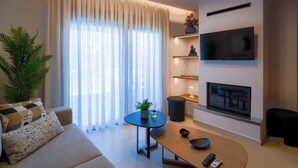 A modern living room with a sofa, a coffee table, a TV mounted on the wall, and a fireplace. - Veneto Luxury Residence with pool in Venerato, Crete (Neo Venerato)