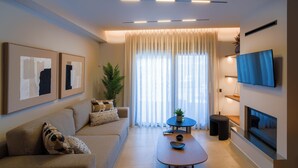 A modern living room with a sofa, coffee table, and a flat-screen TV mounted on the wall. - Veneto Luxury Residence with pool in Venerato, Crete (Neo Venerato)