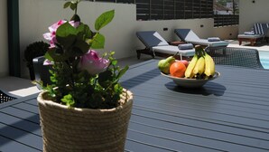 A rooftop terrace with a potted plant, a bowl of fruit, and lounge chairs. - Veneto Luxury Residence with pool in Venerato, Crete (Neo Venerato)