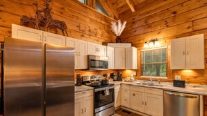 Una cocina moderna con electrodomésticos de acero inoxidable, armarios de madera y una ventana con persianas.