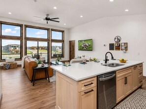 A modern kitchen with a large island, wooden cabinets, and a built-in dishwasher.