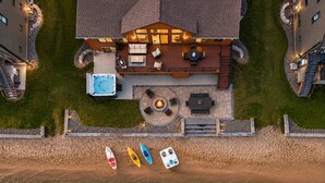 An aerial view of a house with a deck, hot tub, outdoor seating, and kayaks by the water. - Lakefront Home w/Hot Tub & Beach – Sleeps 20 (New Lisbon)