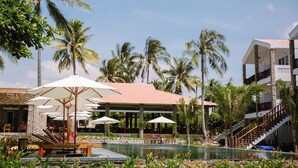 A resort with a pool, outdoor seating, and palm trees.