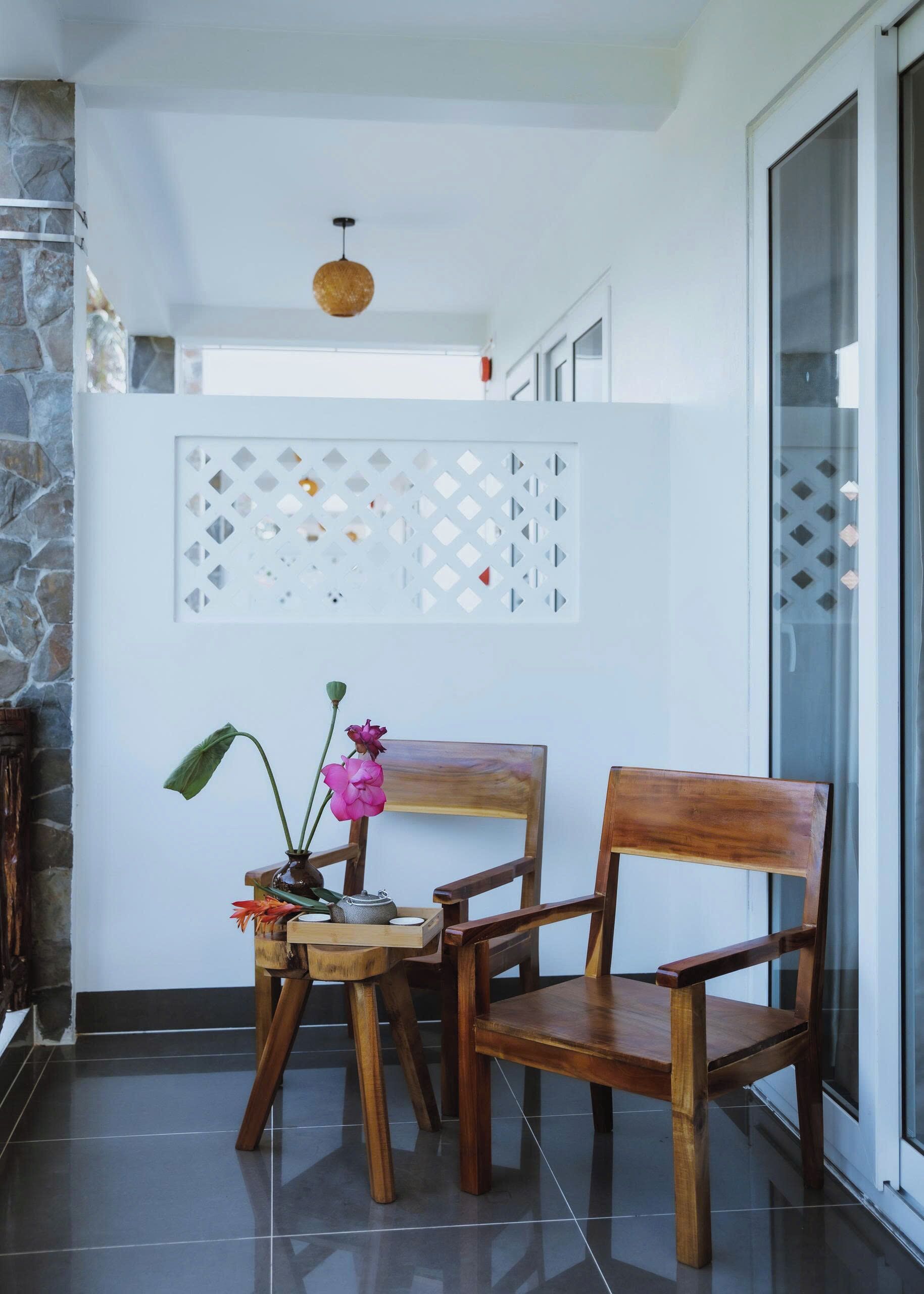A corner of a room with a wooden chair, a small table with a vase of flowers, and a decorative wall panel.
