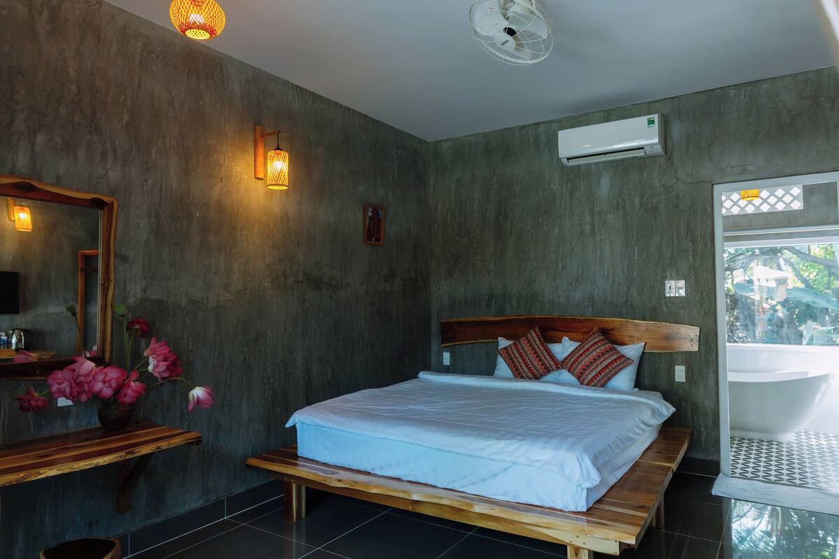 Un dormitorio con una cama grande, cabecera de madera y vistas a un baño con bañera.