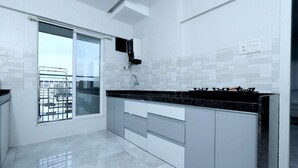 Une cuisine moderne avec des meubles blancs, un plan de travail noir et une cuisinière à gaz.