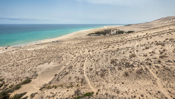 A desert landscape with a beach and a building complex. - Home2Book Esmeralda Beach, Resid. Playa Paraíso (Pajara)