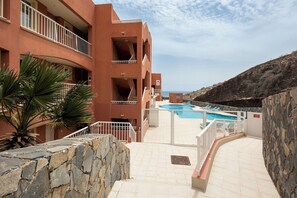 Experience the hotel's multi-level design with balconies and a pool area surrounded by lounge chairs.